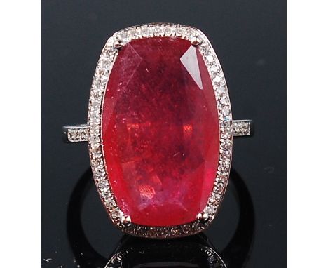 A contemporary 14ct white gold, ruby and diamond ring, the four claw set cushion cut ruby weighing approx 10.35ct, in a surro