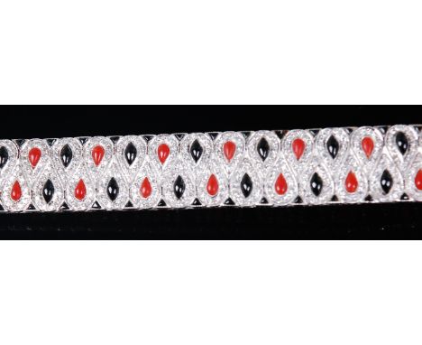 A white metal, diamond, black onyx and coral set bracelet, arranged as interlocking teardrops set with alternating coral and 