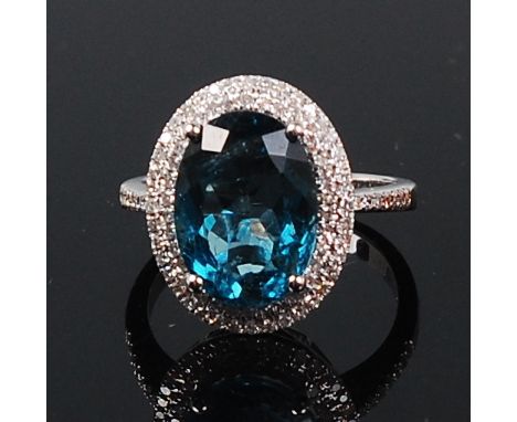 A contemporary 14ct white gold, topaz and diamond ring, arranged as a four claw set oval cut blue topaz weighing approx 6.2ct