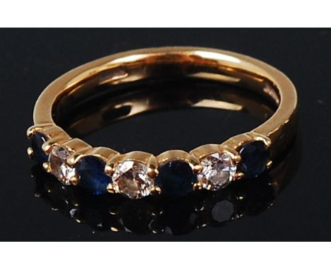 An 18ct gold, sapphire and diamond set band ring, arranged as four round cut sapphires, each dispersed with a single brillian