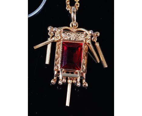 A Burmese 14ct gold and ruby set pendant, the baguette cut ruby measuring approx 9.5 x 7 x 4mm, in a chased gold surround wit