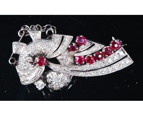 An Art Deco white metal, ruby and diamond set brooch, the whole set with eight claw set rubies above pavé set graduated brill