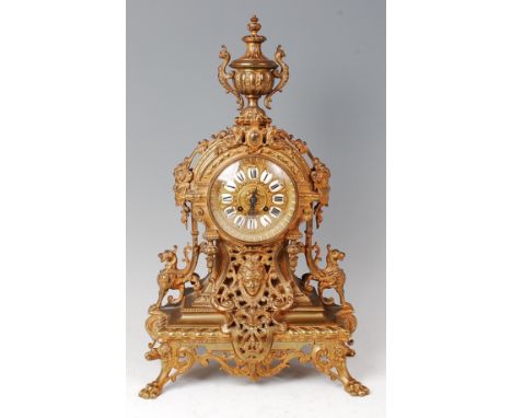 A late 19th century French gilt brass mantel clock, the whole surmounted with a pedestal urn, the dial having raised white en