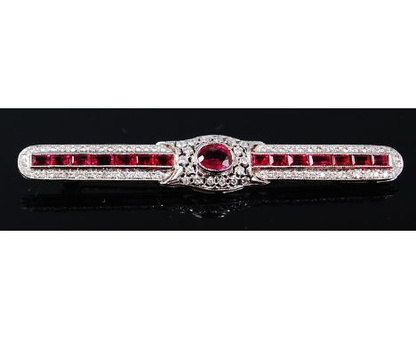 An Art Deco white metal, ruby and diamond set bar brooch, the centre oval cut ruby flanked to either side with seven small ba