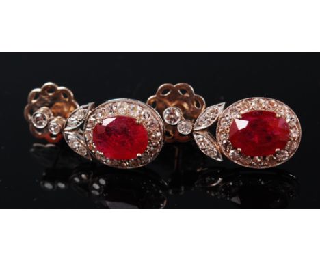 A pair of white metal, ruby and diamond set ear pendants, the four claw set oval cut rubies each weighing approx 1.75ct, in a