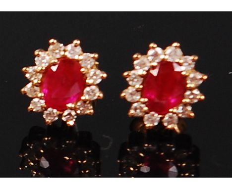 A pair of 18ct gold, ruby and diamond ear studs, as a flower head setting, the centre oval cut ruby weighing approx 0.35ct, i