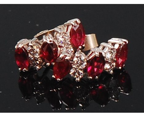 A pair of white metal, ruby and diamond set ear studs, arranged as three marquise cut rubies each dispersed with two small br