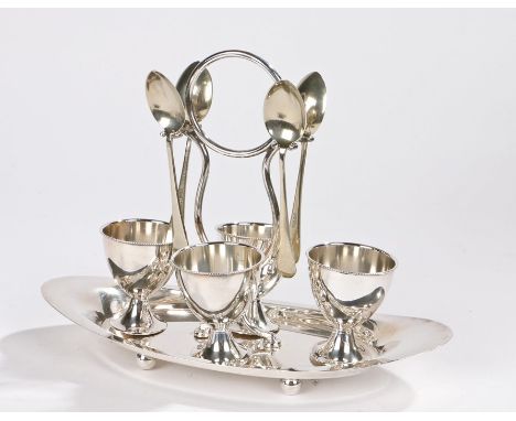 Silver plated egg cruet, the four egg cups with beaded rims, together with four egg spoons, all housed on a stand with circul