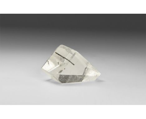 A large freeform-cut piece of very fine, transparent quartz, finely faceted with a needlelike rutile crystal embedded in it, 