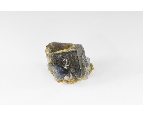 A large square fluorite crystal with a waxy lustre and a deep blue colour; small square crystals to the sides of a paler blue