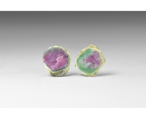A pair of cut and polished, hexagonal, plum red rubies encased in green zoisite with unusual reaction rims around the crystal