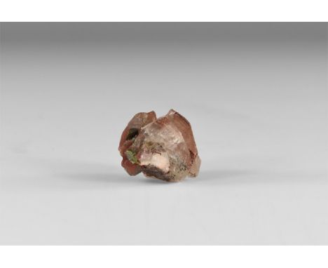 A calcite crystal with red oxide colouring and sphalerite growths to one end, in white card tray with label reading: 'CALCITE