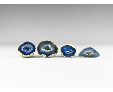 A group of four cut and polished agate geode halves displaying bands of varying blue colour and with cavities to the centre w