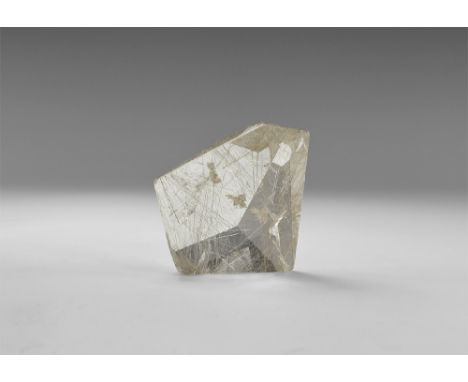A freeform facetted rutilated quartz from Brazil with numerous bright golden rutile needles in various orientations in white 