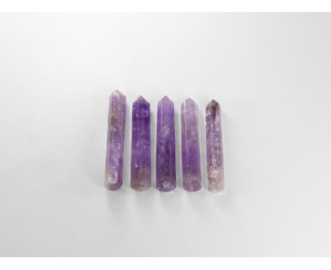 A group of five cut and polished amethyst obelisks or massage tools ranging in colour from light to dark purple and with rain