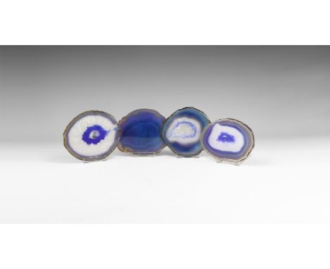 A group of four cut and polished agate slices with bands of purple-blue colour to the borders, three with honeycomb quartz cr