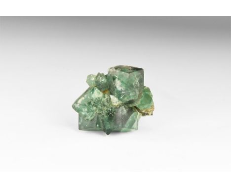 A fine specimen of Cornish fluorite, consisting of numerous intergrown green cubes, in white card tray with old adhesive tape