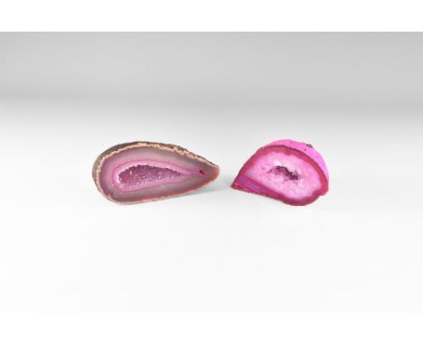 Two cut and polished agate geode halves with bands of pink to purple colour; in the centre a cavity filled with clusters of q