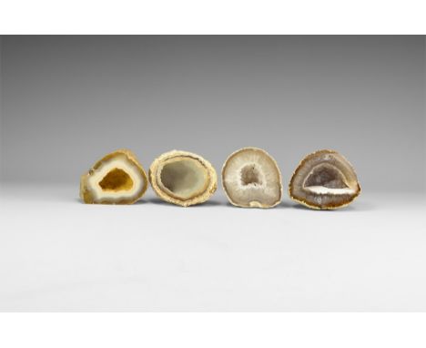 A group of four agate geode halves with bands of colour and honeycomb crystal growth to the edges, cavities to the centre wit