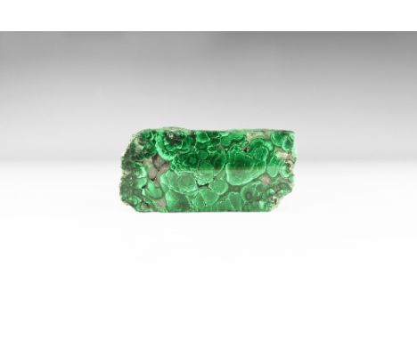 A large piece of cut and polished malachite with lustrous sheen of pale and dark green, pale crystals between nodules. See Bo