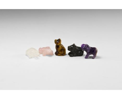 A group of carved gemstone animals including: a quartz tortoise, tigers eye cat, labradorite hippo, amethyst elephant, rose q