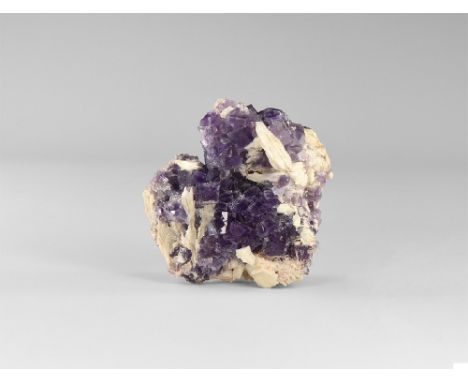 A specimen comprising transparent cubic crystals of purple fluorite, surmounted by white, bladed crystals of barite, some flu