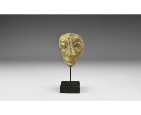 Pliocene Period, 5.2-2.5 million years BP. A Mastodon fossil bone carved with later image of a human face; mounted on a custo