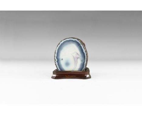 A large cut and polished agate slice showing bands of pale blue-grey and milky white to the internal structure; mounted on a 