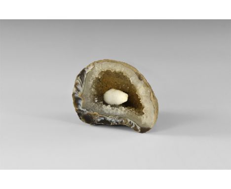 A cut and polished agate geode lined with quartz crystals to the interior cavity, and a single large white calcite scalenohed