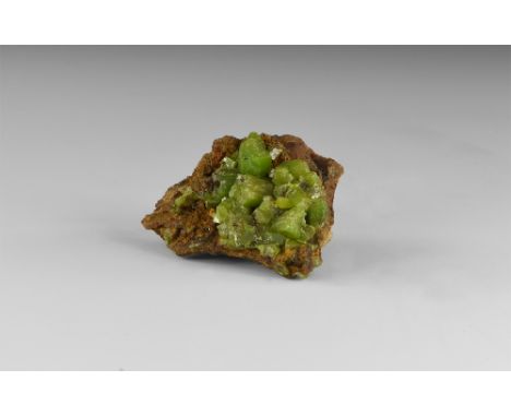 A cluster of green pyromorphite crystals on a matrix in the form of hexagonal prisms terminated by the basal planes, from Tsc