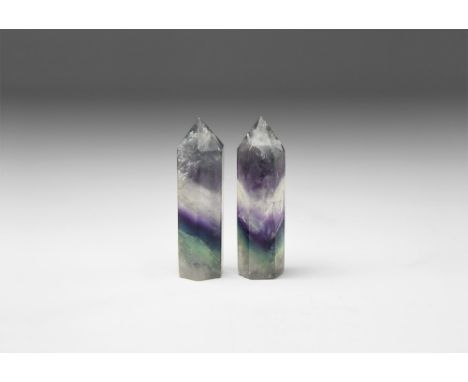 A pair of prism cut fluorite obelisk points with bands of colour ranging from jade green, purple and clear, with 'rainbow' re