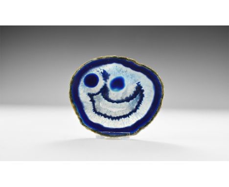 A cut and polished agate slice with deep blue border, white honeycomb crystals to the centre and with a 'smiley face' formati