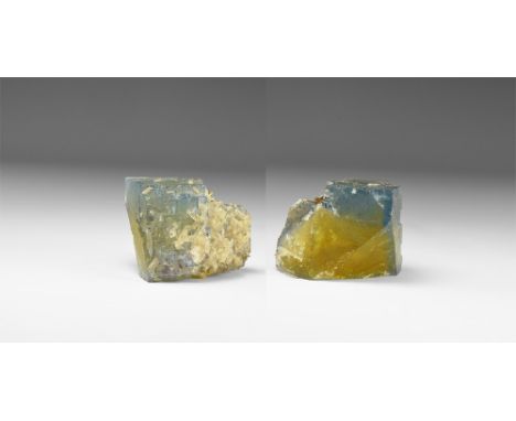 A large fluorite crystal with angled edges and ranging in colour from yellow to purple; clusters of small calcite crystals to