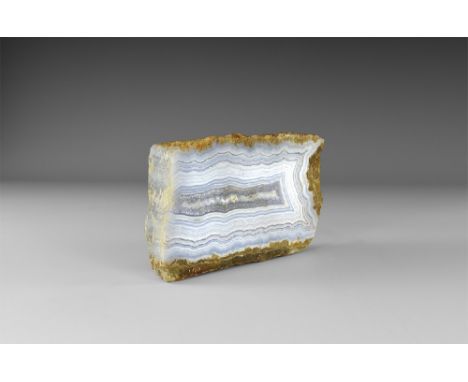 A large rectangular piece of blue lace agate in pale blue and cream with central band of honeycomb-shaped crystals. See Bonew