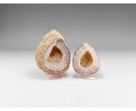 A large agate geode with section removed from the top to reveal internal structure of bands of pale blue and yellow with clus