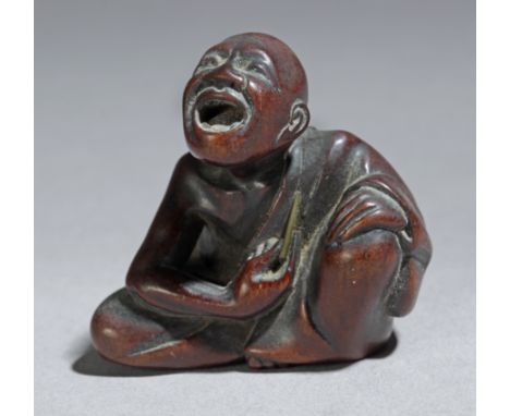 A 19th century Japanese netsuke from Meiji period. Signed Hokei on the base. In carved wood portraying a sat man holding a st