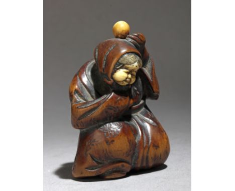 A mid 19th century Japanese netsuke from Edo period. Not signed. In carved ivory and wood portraying a kneeling Okame flaunti