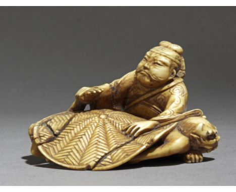 A Japanese netsuke circa 1900. In carved ivory portraying a Shoki subuying two Onis under a rounded rug, 29,4x45,5x37,4 mm. 1