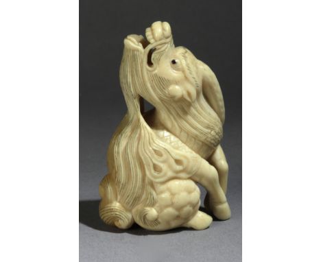 A Japanese netsuke circa 1800 from Edo period. Not signed. In carved walrus ivory and horn portraying a 'Kirin' with his head
