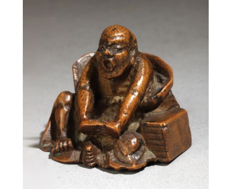 A 19th century Japanese netsuke from Meiji period. Not signed. In carved wood portraying an elder man sat on the floor and st