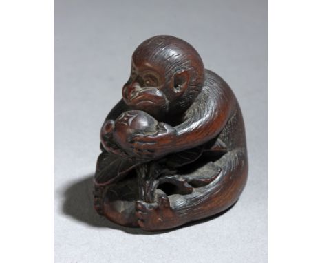 A 19th century Japanese netsuke from Meiji period. Signed on the base. In carved wood portraying a monkey sat on the floor wh
