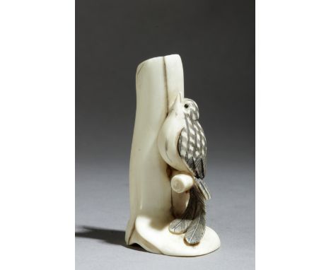 A Japanese netsuke circa 1975-2000 from period Showa-Hesei. In carved ivory portraying a bird resting over a branch with his 