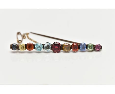 A YELLOW METAL MULTI GEMSTONE BAR BROOCH, designed with a row of vary cut gemstones, each claw set, to include garnet, sapphi