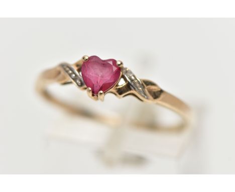 A 9CT YELLOW GOLD , RUBY AND DIAMOND RING, designed with a heart cut ruby, four claw set between cross detailed shoulders set