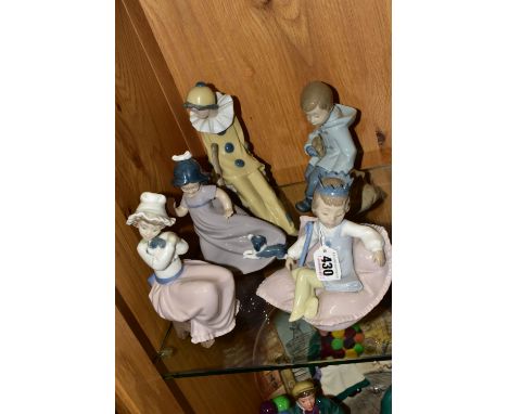 FIVE NAO FIGURES, to include a girl wearing a party hat seated on a large cushion, a seated girl holding a puppy, a boy holdi