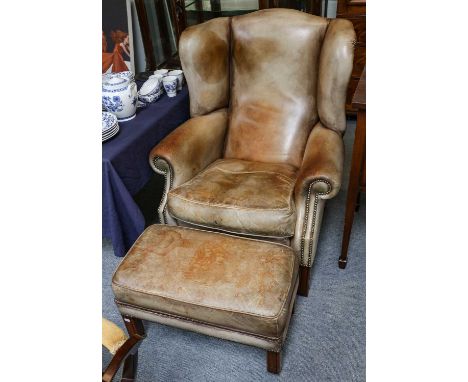 A tan leather studded wing back chair on mahogany frame with matching footstool (2)No tears. Some light scuffs and the leathe