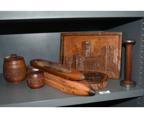 A selection of treeen, including bobbin shuttles, carved lidded pots and carved decorative scenes.