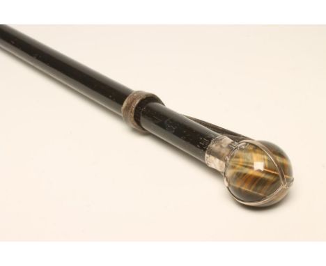 A GENTLEMAN'S LATE VICTORIAN SILVER MOUNTED WALKING CANE, the tiger's eye pommel overlaid in silver as an orb, maker's mark i