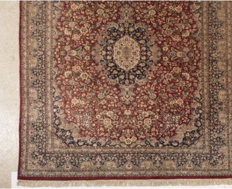 A PAKISTANI KASHAN CARPET, the brick red field with navy blue and ivory central gul and similar spandrels and with all over i