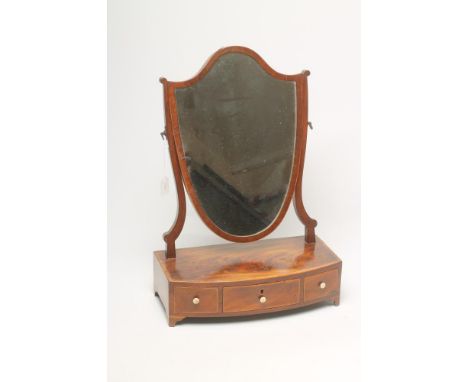 A GEORGIAN MAHOGANY TOILET MIRROR, late 18th century, the shield shaped plate on scrolled uprights, the banded bowed box base